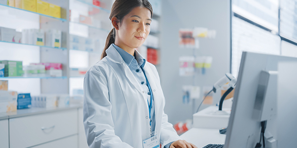 A pharmacist standing and working on a computer