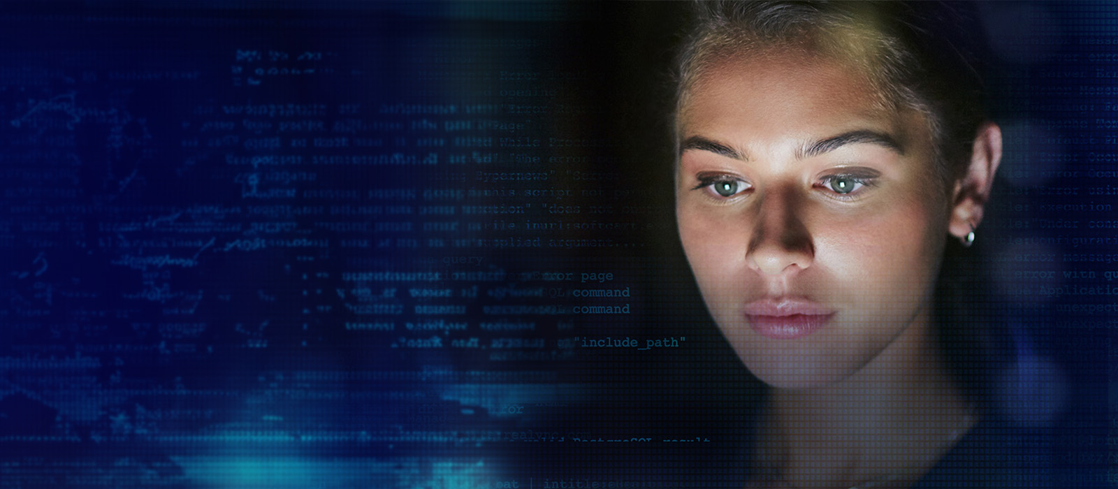 Woman’s face highlighted behind a screen of code