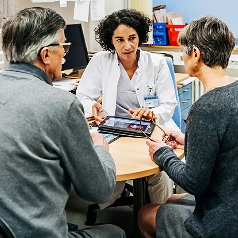 A medical professional talking to a senior couple.