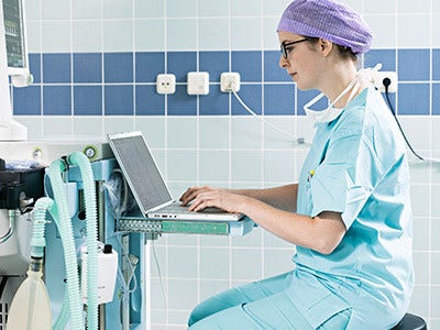 doctor in scrubs using laptop