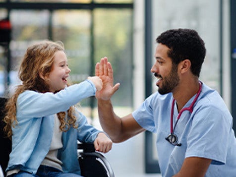 A child in wheelchair giving high-five to doctor